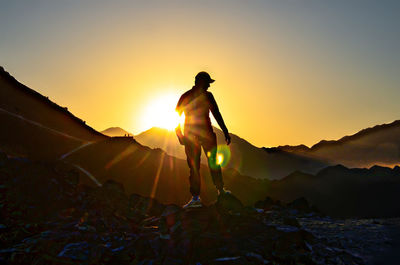 Silhouette man standing on mountain against sky during sunset