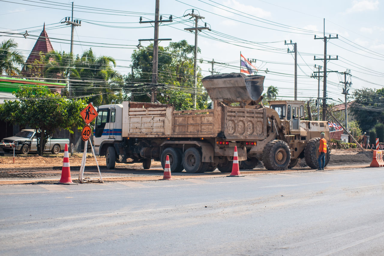 MAN WORKING ON ROAD AGAINST SKY