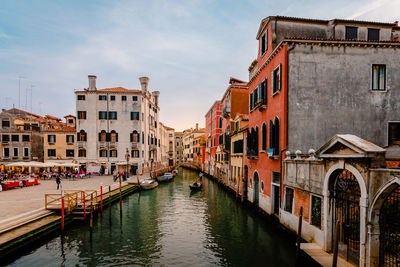 Venetian gondola as it sails on characteristic canal with colorful buildings at sunset