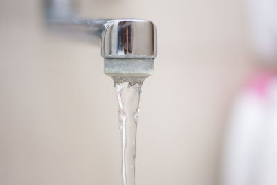 Water running from a bathroom faucet with soap in the background.