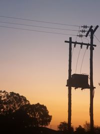 Low angle view of silhouette electricity pylon against sky during sunset