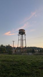 Windmill on field against sky during sunset