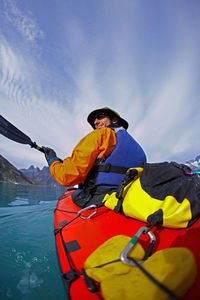 Man traveling on a sea-kayak though the fjords of eastern greenland