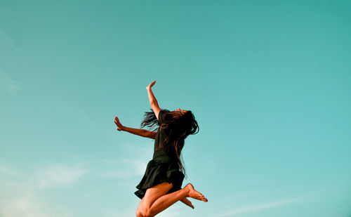 Woman with arms raised against sky