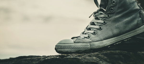 Low section of person wearing canvas shoe standing on rock