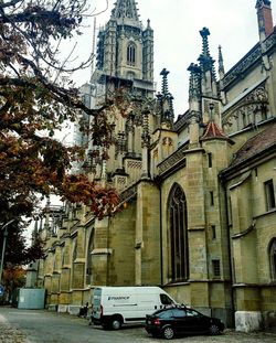 Cars parked outside cathedral against sky in city