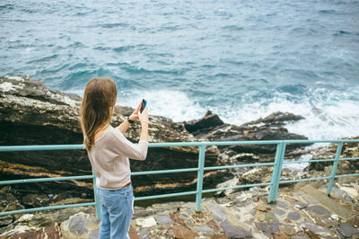 Woman sitting on rock by sea