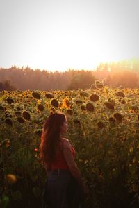 Woman standing on field against sky during sunset