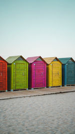 Beach huts against buildings against clear sky