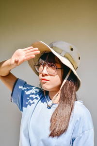 Young woman shielding eyes against wall