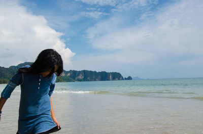 Woman standing on beach against sky