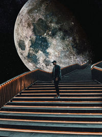 Rear view of man walking on staircase at night