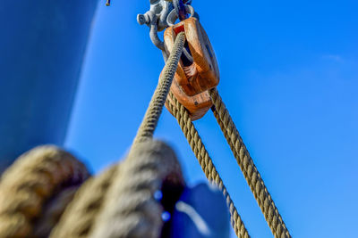 Low angle view of pulley against blue sky