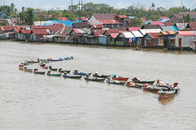 High angle view of boats in river by buildings