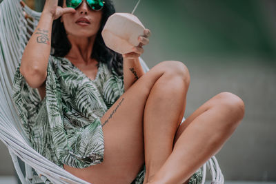 Midsection of young woman sitting outdoors