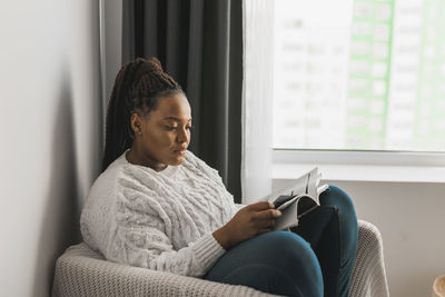 Young woman using laptop while sitting on sofa at home