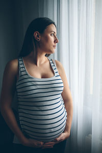 Pregnant woman standing by window at home