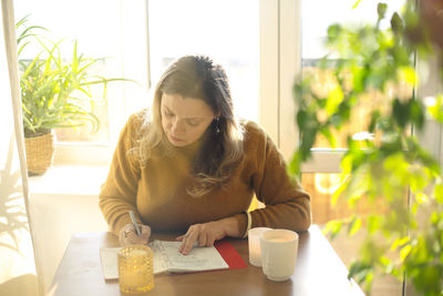 Mature woman writing in diary at home