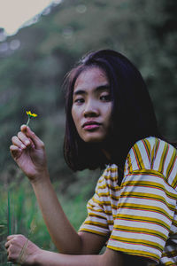 Portrait of young woman holding plant