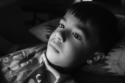 Close-up of thoughtful boy sleeping on bed in darkroom