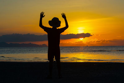 Silhouette man standing at beach during sunset