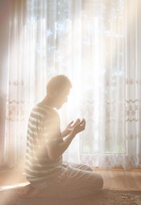 Full length of man sitting on window