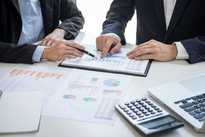 Midsection of business people working on table