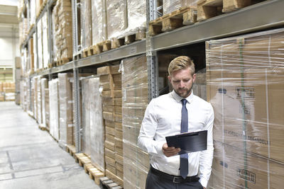 Businessman looking at clipboard in warehouse