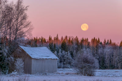 Scenic view of snow covered field against sky at sunset