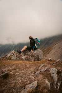 Man standing on rock against sky