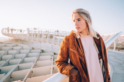 Young woman standing on snow against clear sky