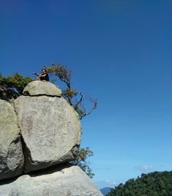 Low angle view of rocks against clear blue sky