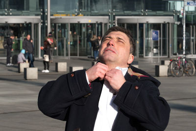 Stressful businessman adjusting shirt in city