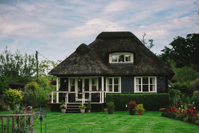 House and trees against sky in lawn