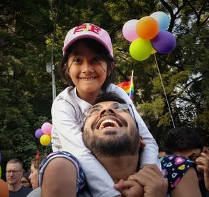 Portrait of smiling friends with balloons at park