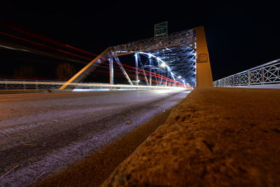 Light trails on bridge in city against sky at night