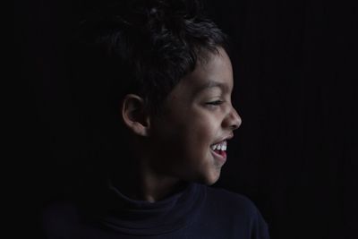 Portrait of smiling young man against black background