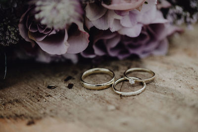 Close-up of wedding rings by flowers on wooden table