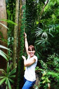 Portrait of smiling young woman standing by plants