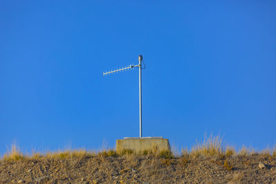 Low angle view of windmill on field against clear blue sky