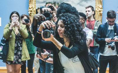 Young woman photographing with mobile phone while standing outdoors