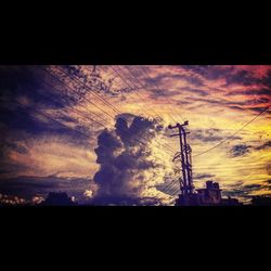 Low angle view of silhouette trees against dramatic sky