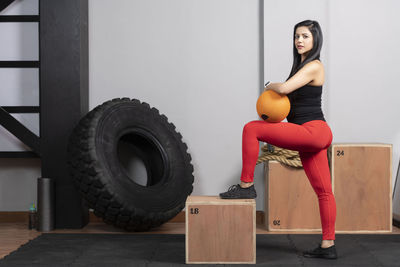 Portrait of young woman sitting against wall