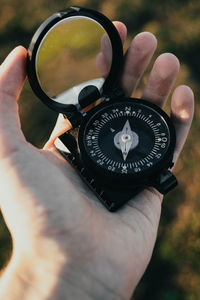 Close-up of a person holding a compass outdoors.