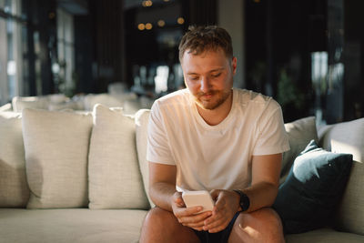 Portrait of young man sitting on sofa at home