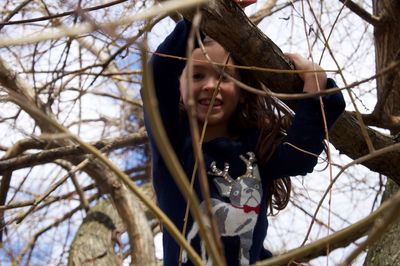 Portrait of girl by bare tree against sky