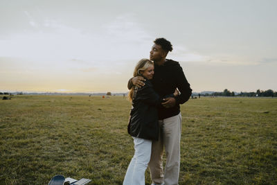 Young woman embracing female friend in park during sunset