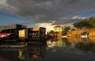 Boats in river against cloudy sky