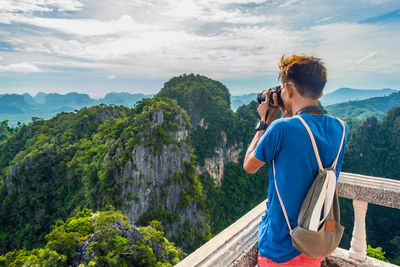 Man photographing mountains against sky