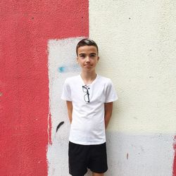 Portrait of boy standing against wall